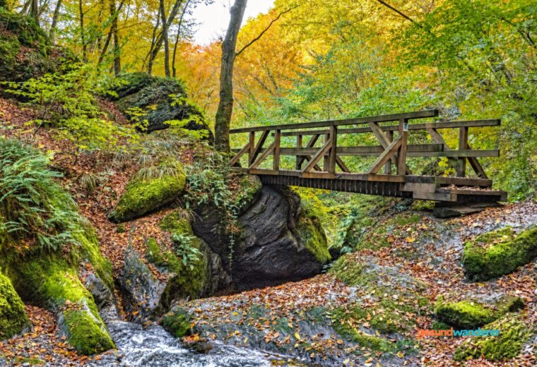 Holzbrücke über einen Bach zwischen Felsen im Wald