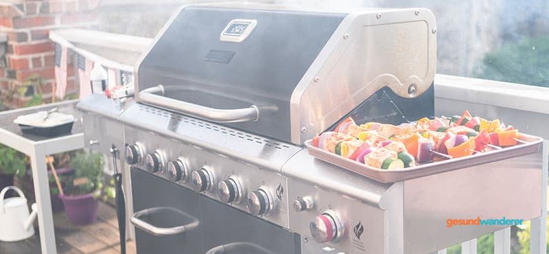 Gemüsespieße auf einem Tablett neben einem Gasgrill