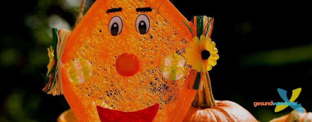 Kind hält einen selbst gestalteten orangefarbenen Drachen