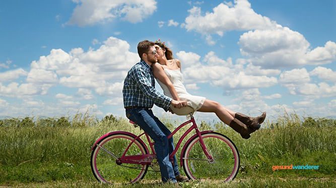 Zwei Menschen machen mit dem Fahrrad Pause in einer grünen Landschaft