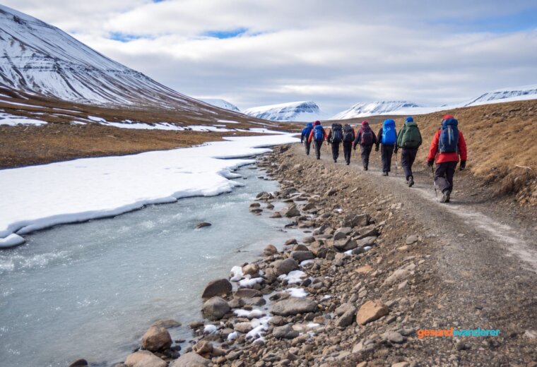 Weites Tal mit Schmelzwasser, Schnee und einer Wandergruppe auf Spitzbergen