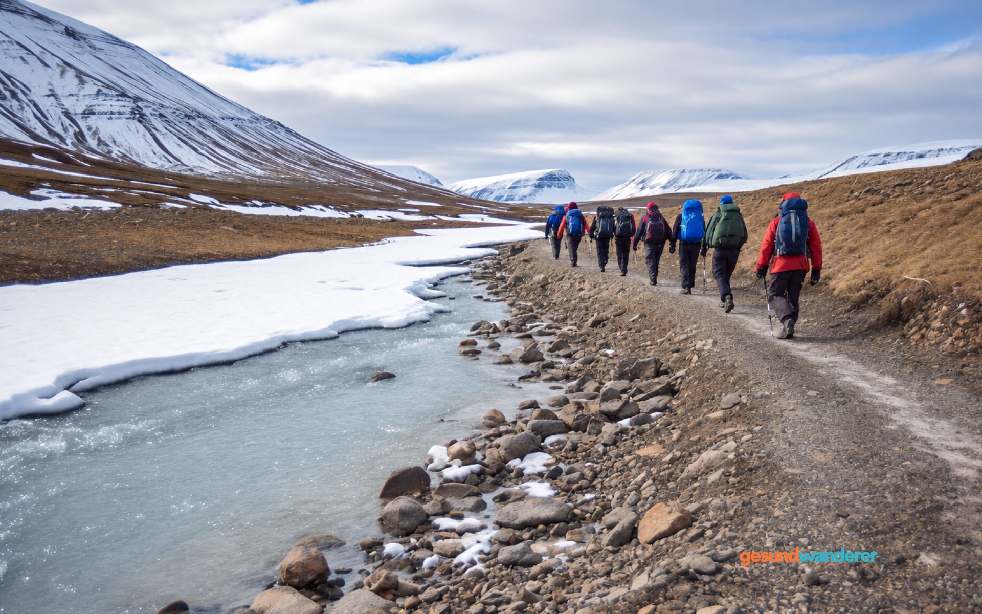 Weites Tal mit Schmelzwasser, Schnee und einer Wandergruppe auf Spitzbergen
