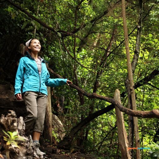 Wanderin auf einem schmalen Weg im dichten grünen Wald