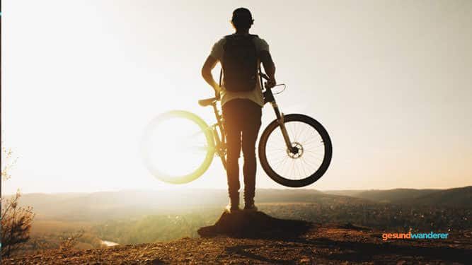 Person mit einem Fahrrad im Gegenlicht